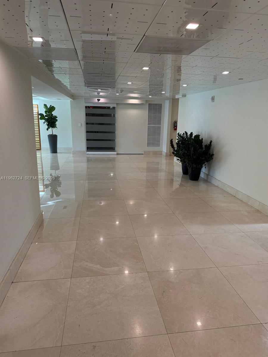 A bright, tiled lobby features a glass-paneled door, potted plants, and a drop ceiling — 540 Brickell Key Dr # 1505, Miami FL 33131, MIAMI, FL
