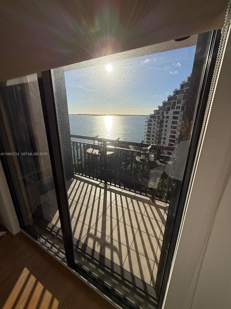 A view of a balcony overlooking a body of water and a neighboring building — 540 Brickell Key Dr # 1505, Miami FL 33131, MIAMI, FL