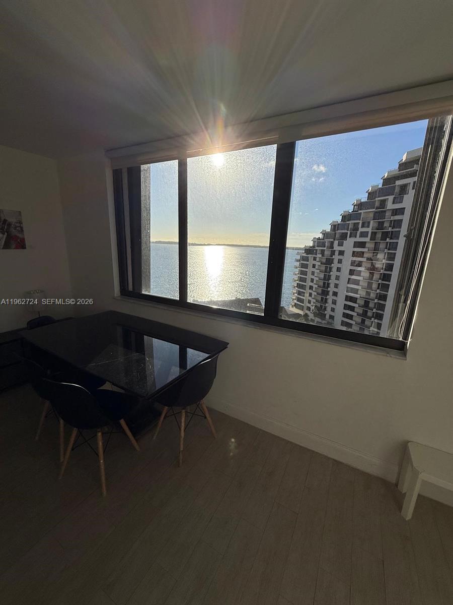 A dining area features a black table and chairs set before a large window overlooking water — 540 Brickell Key Dr # 1505, Miami FL 33131, MIAMI, FL