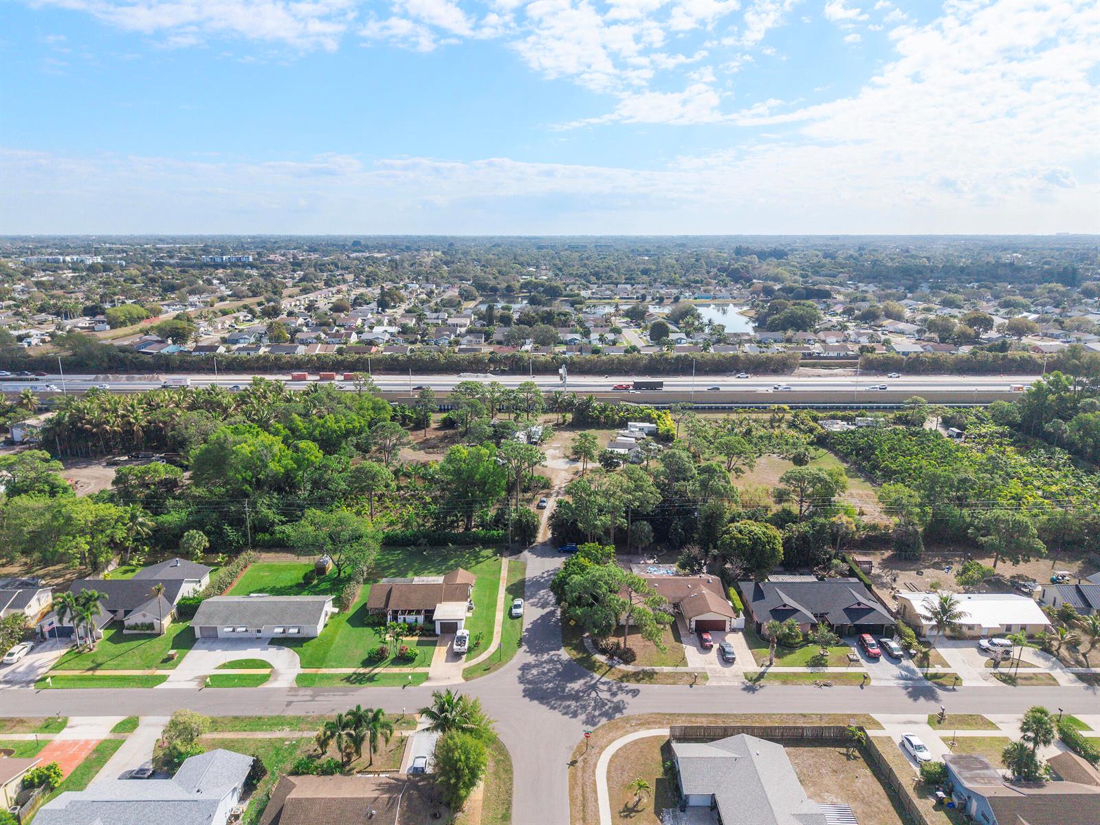 An aerial view shows a residential neighborhood with houses, trees, and a nearby highway — 5387 80th Trail S, Lake Worth FL 33467, LAKE WORTH, FL