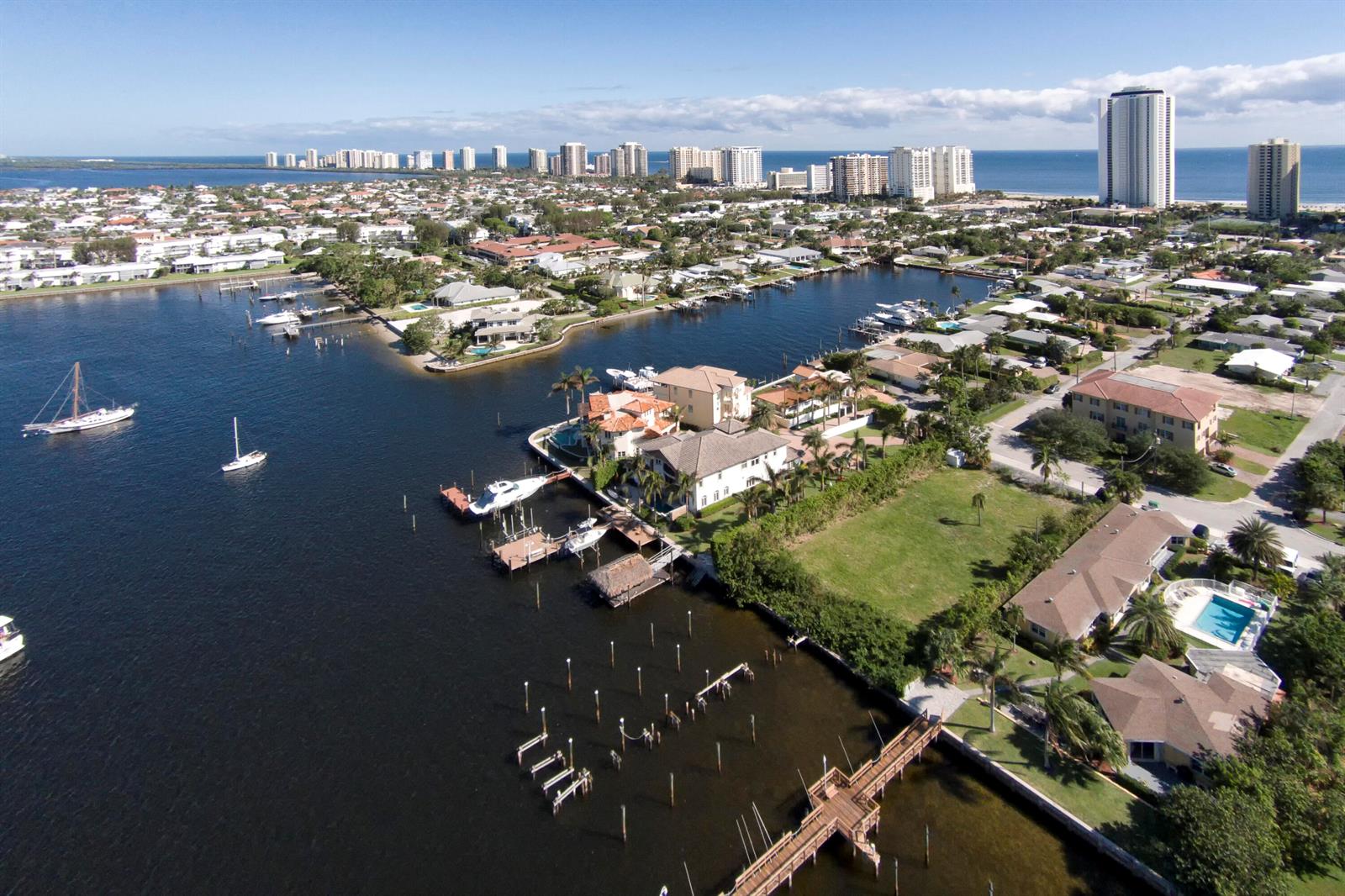 An aerial view of a waterfront residential neighborhood with docks, boats, and high-rise buildings — 2715 Lake Drive, Riviera Beach FL 33404, RIVIERA BEACH, FL