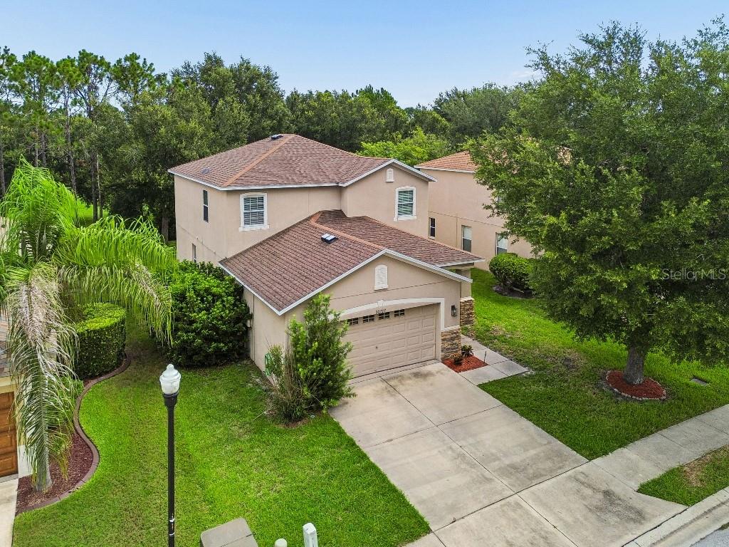 An aerial view of a two-story suburban house with a tan stucco exterior and garage — 30737 WHITE BIRD AVENUE, WESLEY CHAPEL, FL