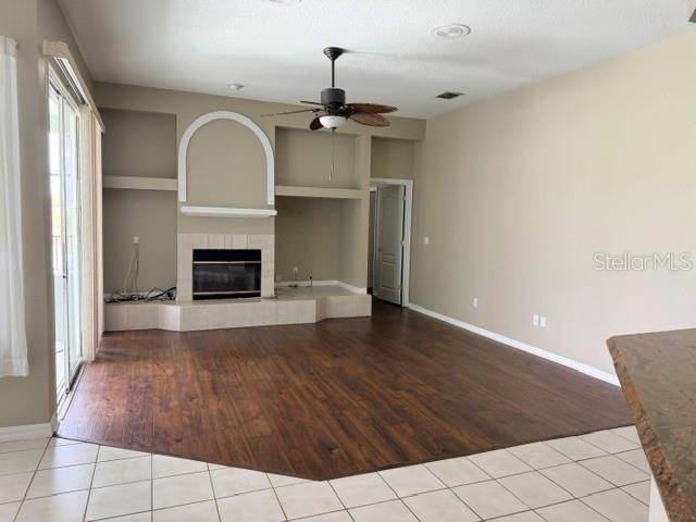 A living room features a fireplace, built-in shelving, a ceiling fan, and dark wood flooring — 16525 MAJESTIC COURT, CLERMONT, FL