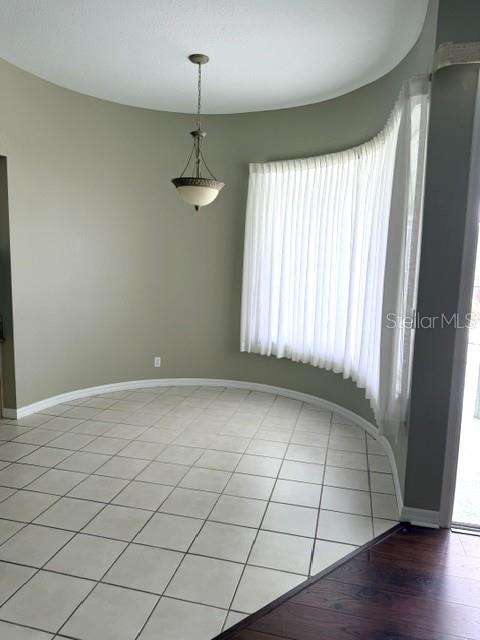A dining area features light-colored tile flooring, a curved wall of windows, and a pendant light — 16525 MAJESTIC COURT, CLERMONT, FL