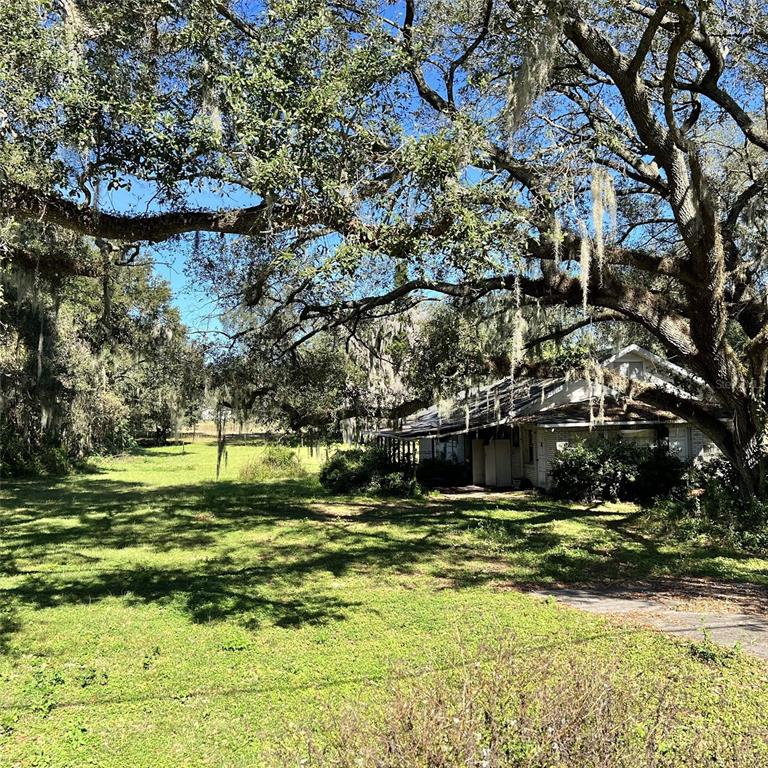 A single-story house sits on a grassy lot shaded by large, moss-covered oak trees — 4504 E COUNTY ROAD 540A, LAKELAND, FL