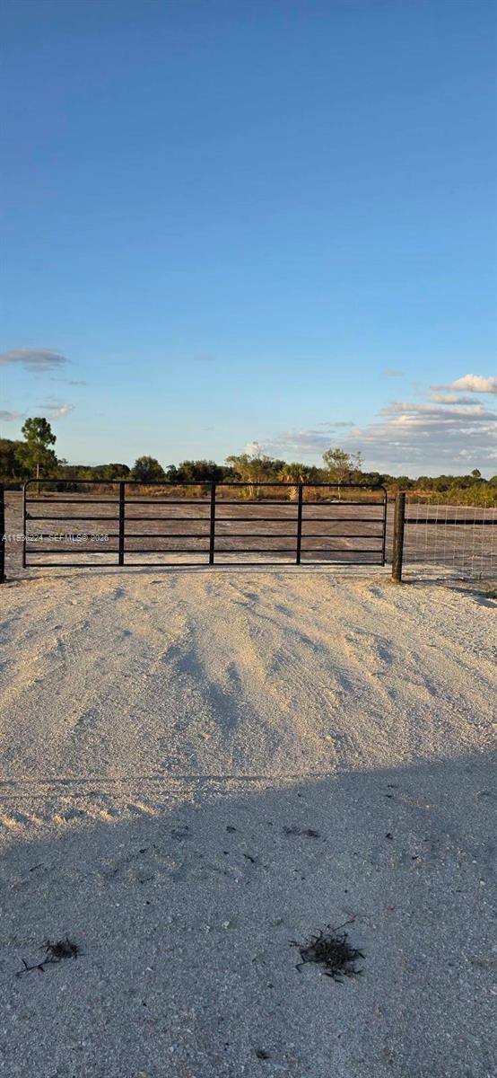 A black metal gate stands at the entrance of a gravel driveway leading to open land — 17385 NW 314 st, Okeechobee FL 34972, OKEECHOBEE, FL