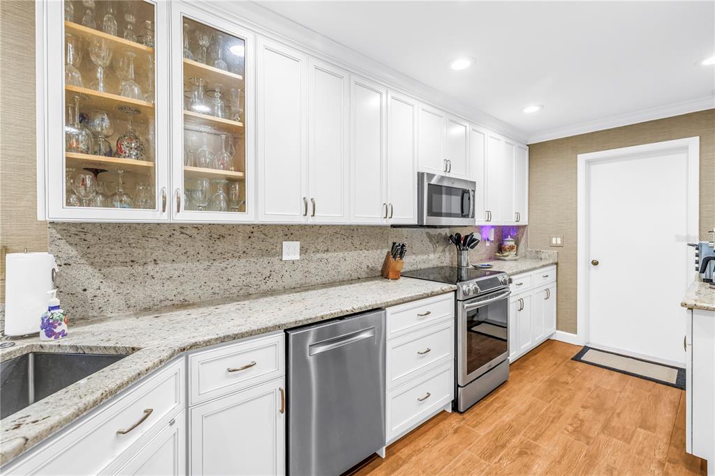 An open-concept living and dining area features wood-look tile flooring, a fireplace, and French doors — 812 AMELIA COURT NE, ST PETERSBURG, FL