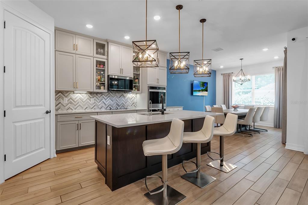 A modern open-concept living room features a large gray sectional sofa and a kitchen island — 7336 GREAT EGRET BOULEVARD, SARASOTA, FL