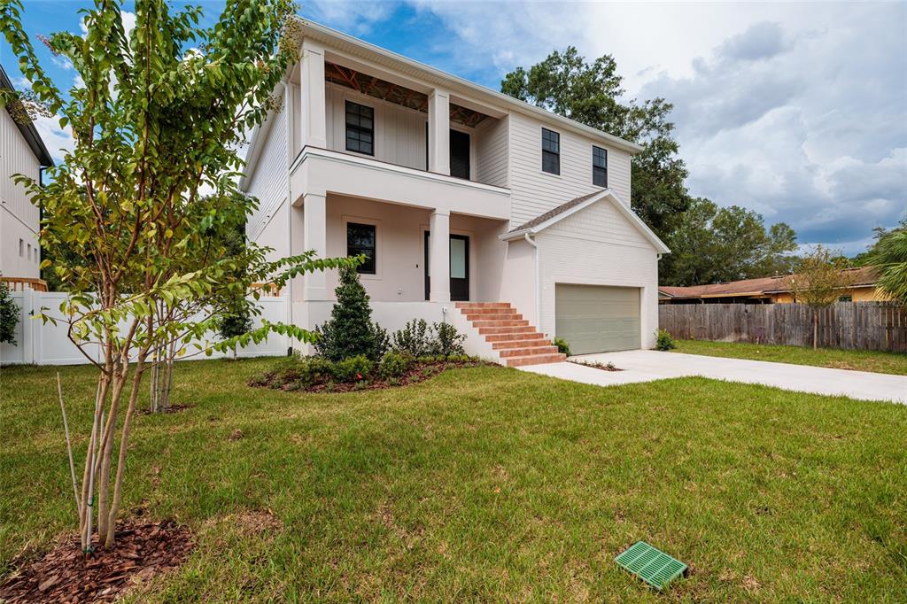 A two-story house with a raised front porch, brick steps, and an attached garage — 4703 W KNIGHTS AVENUE, TAMPA, FL