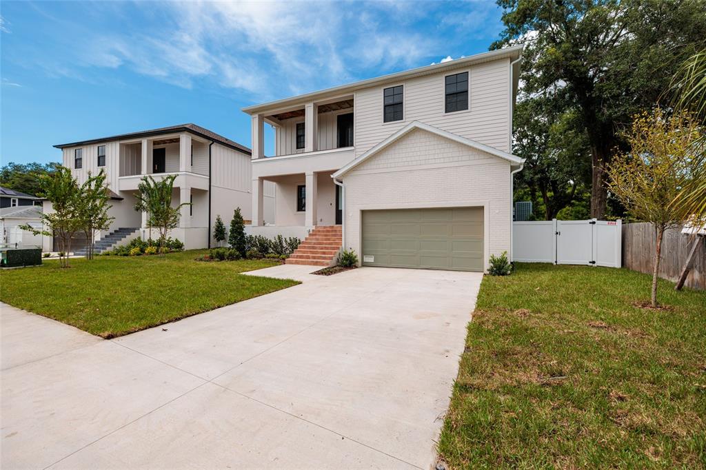 A two-story house with a light-colored exterior, a front-facing garage, and a brick-stepped entrance — 4703 W KNIGHTS AVENUE, TAMPA, FL