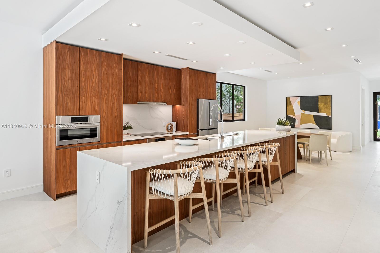 A modern kitchen features wood cabinetry, a white marble island, and four woven bar stools — 2984 Coconut Ave, Coconut Grove FL 33133, COCONUT GROVE, FL
