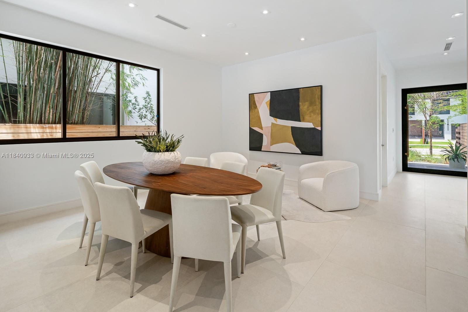 A dining room features an oval wooden table, white chairs, abstract art, and large windows — 2984 Coconut Ave, Coconut Grove FL 33133, COCONUT GROVE, FL