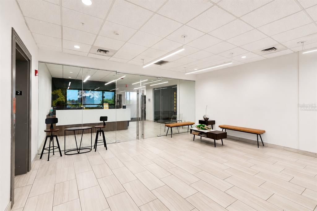 A modern office reception area features tile flooring, glass partitions, and minimalist bench seating — 3707 W CHERRY STREET, TAMPA, FL