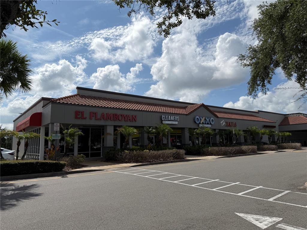 A single-story commercial strip mall with multiple storefronts under a tiled roof — 12141 S ORANGE BLOSSOM TRAIL, ORLANDO, FL