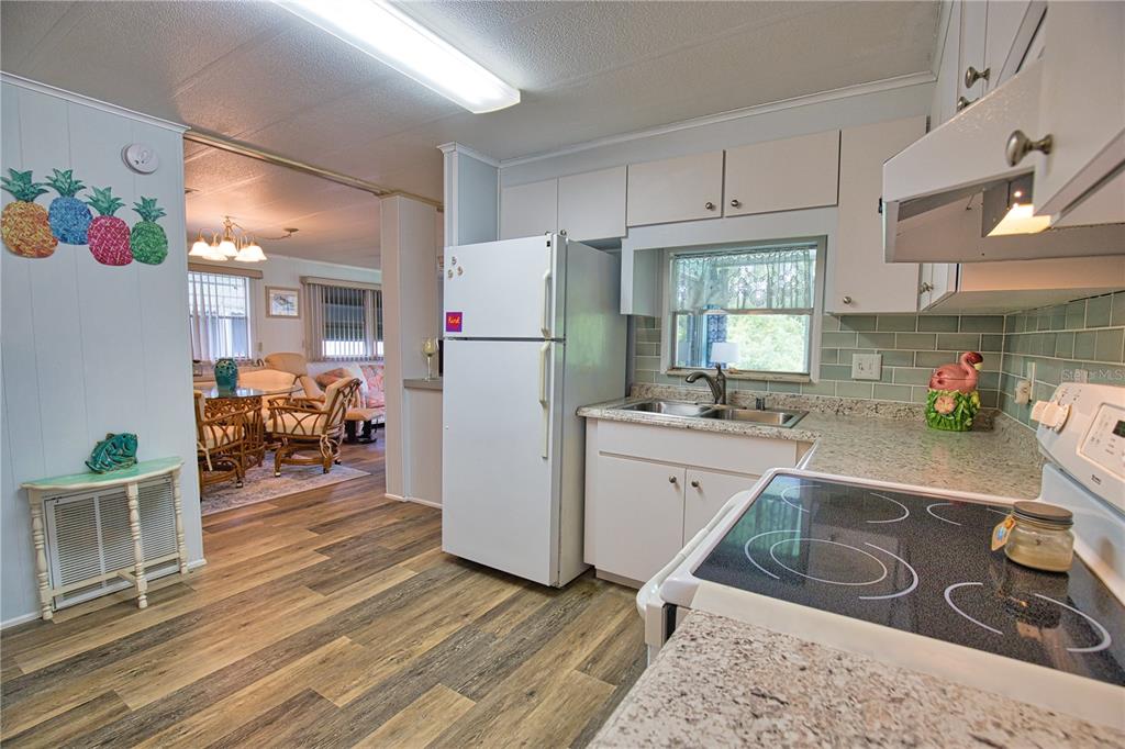 A kitchen with white cabinets, a white refrigerator, and a view into a living area — 236 N FIJI CIRCLE, ENGLEWOOD, FL