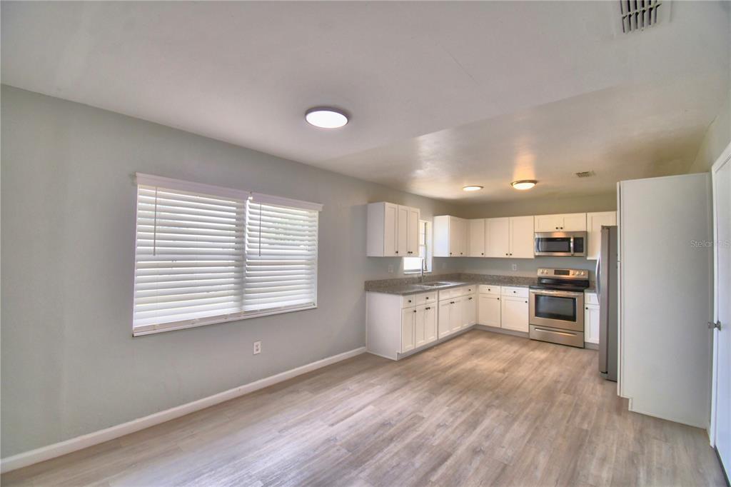 A kitchen with white cabinets, stainless steel appliances, and light wood-look flooring — 105 BYRON PLACE, WINTER HAVEN, FL