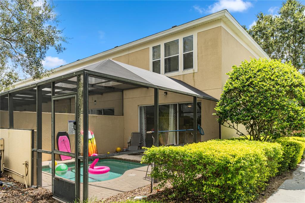 A two-story house features a screened-in patio with a small pool and landscaping — 7683 FITZCLARENCE STREET, KISSIMMEE, FL