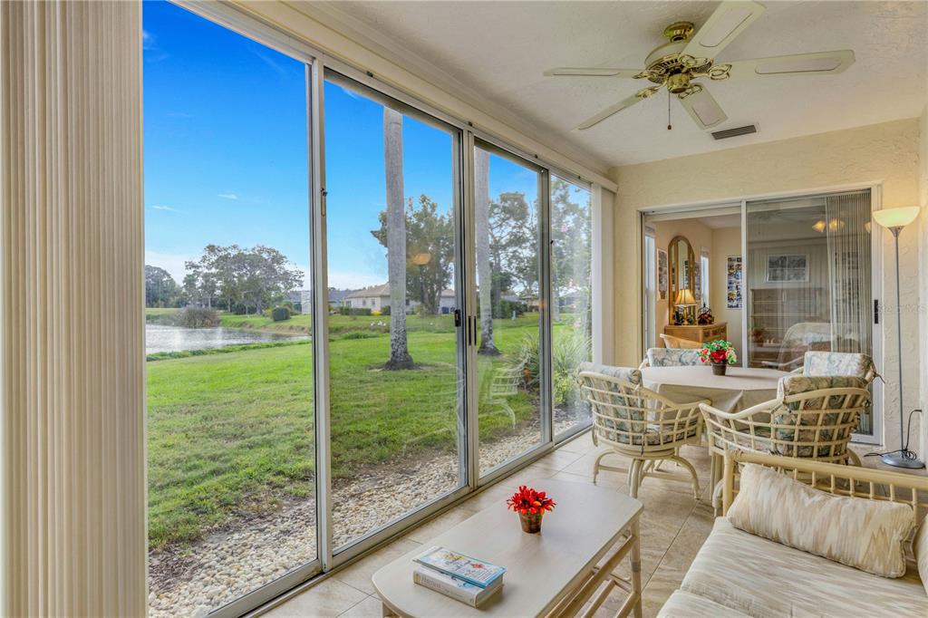 A sunroom with tile flooring, a ceiling fan, and sliding glass doors overlooking a pond — 3242 RINGWOOD MEADOW UNIT 76, SARASOTA, FL