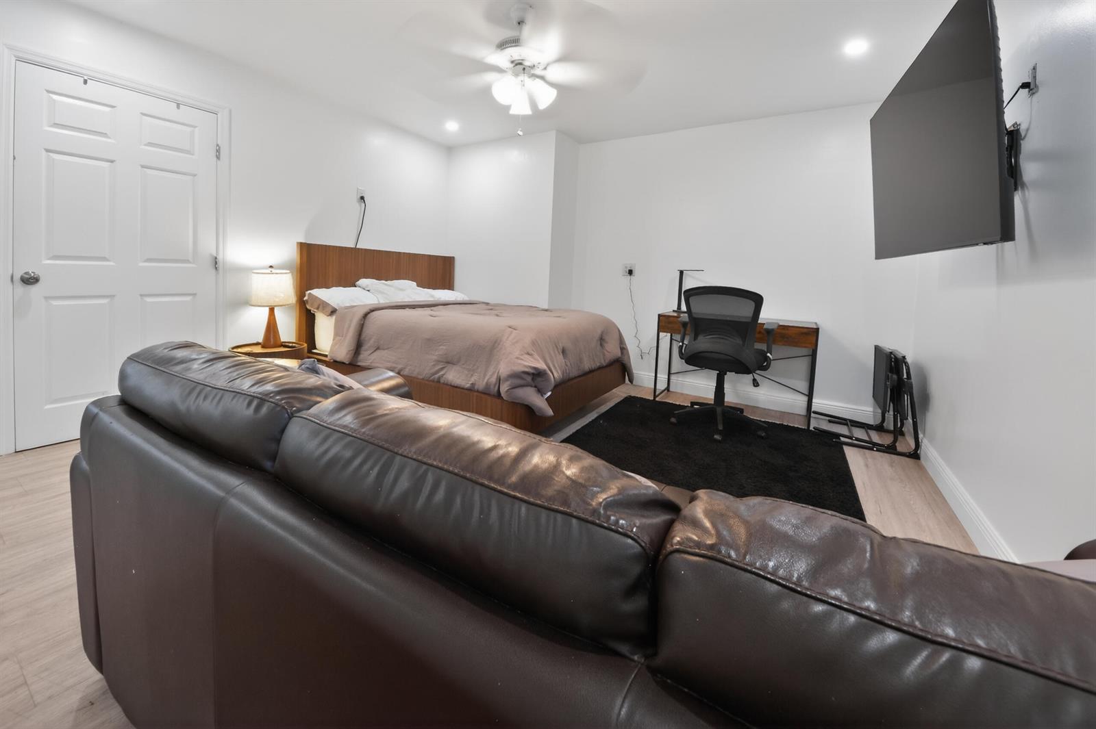 A bedroom features a bed, a desk with a chair, a sofa, and a wall-mounted television — 10754 Tamis Trail Unit B, Lake Worth FL 33449, LAKE WORTH, FL