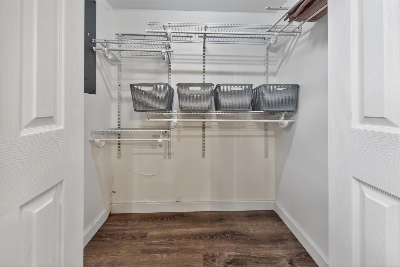 A walk-in closet features white wire shelving, four gray storage baskets, and wood-look flooring — 10754 Tamis Trail Unit B, Lake Worth FL 33449, LAKE WORTH, FL