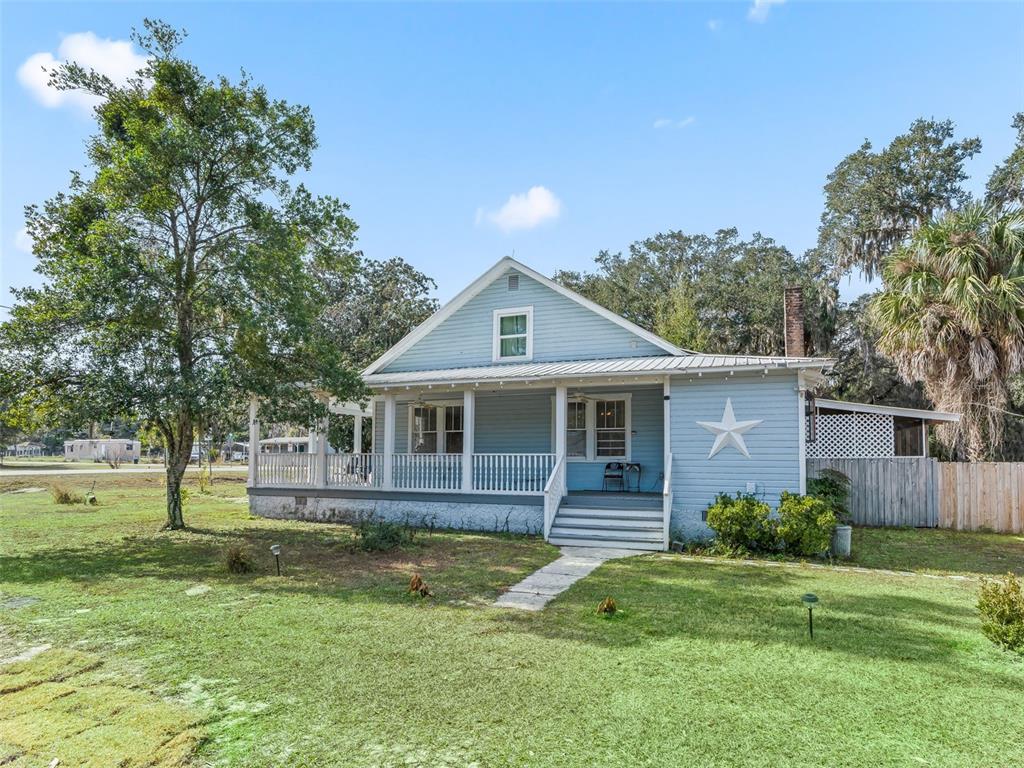 A light blue, single-story house with a wrap-around porch and a white star decoration — 10487 SE HIGHWAY 42, SUMMERFIELD, FL