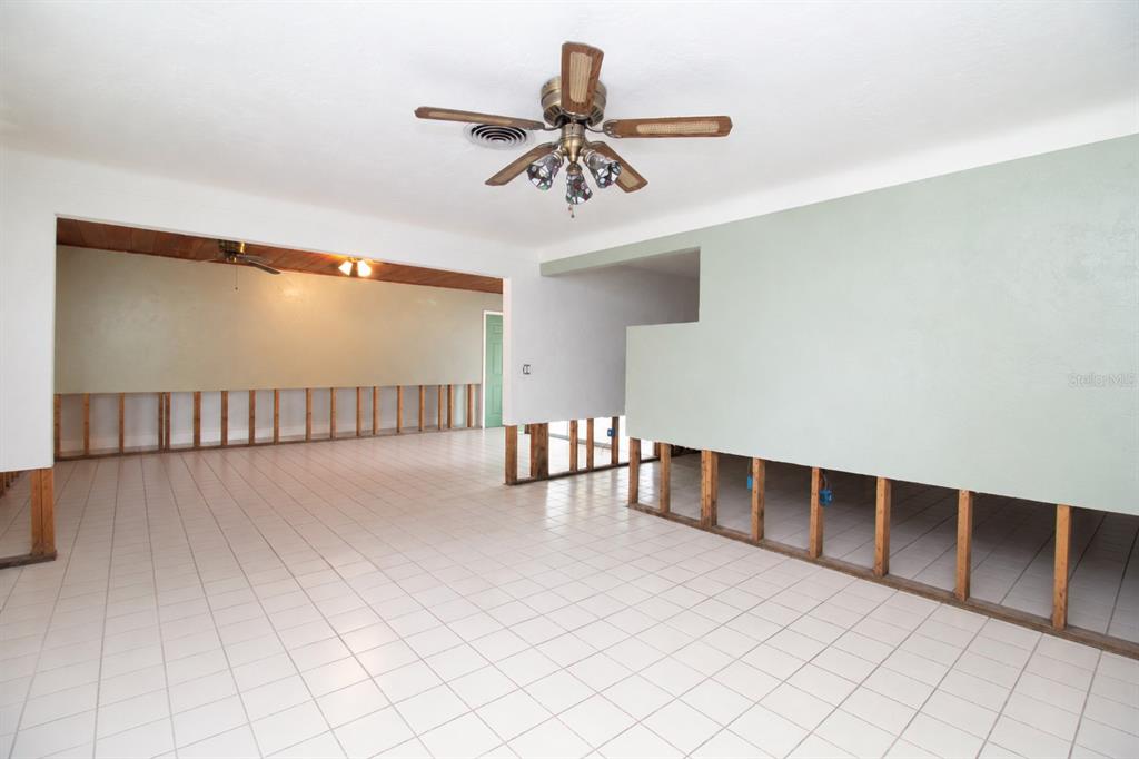 An interior room with white tile flooring and walls partially stripped to the wooden studs — 525 HAMPTON AVENUE NE, ST PETERSBURG, FL