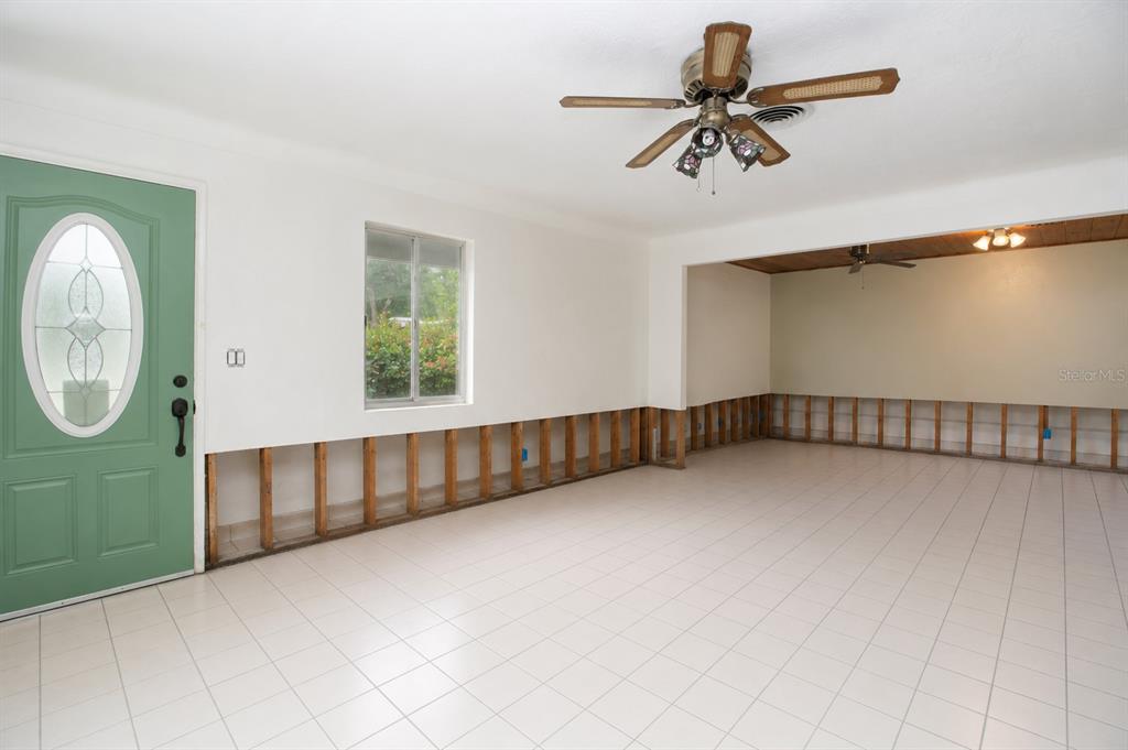 A room with white tile flooring, a ceiling fan, a green front door, and a tarp-covered area — 525 HAMPTON AVENUE NE, ST PETERSBURG, FL