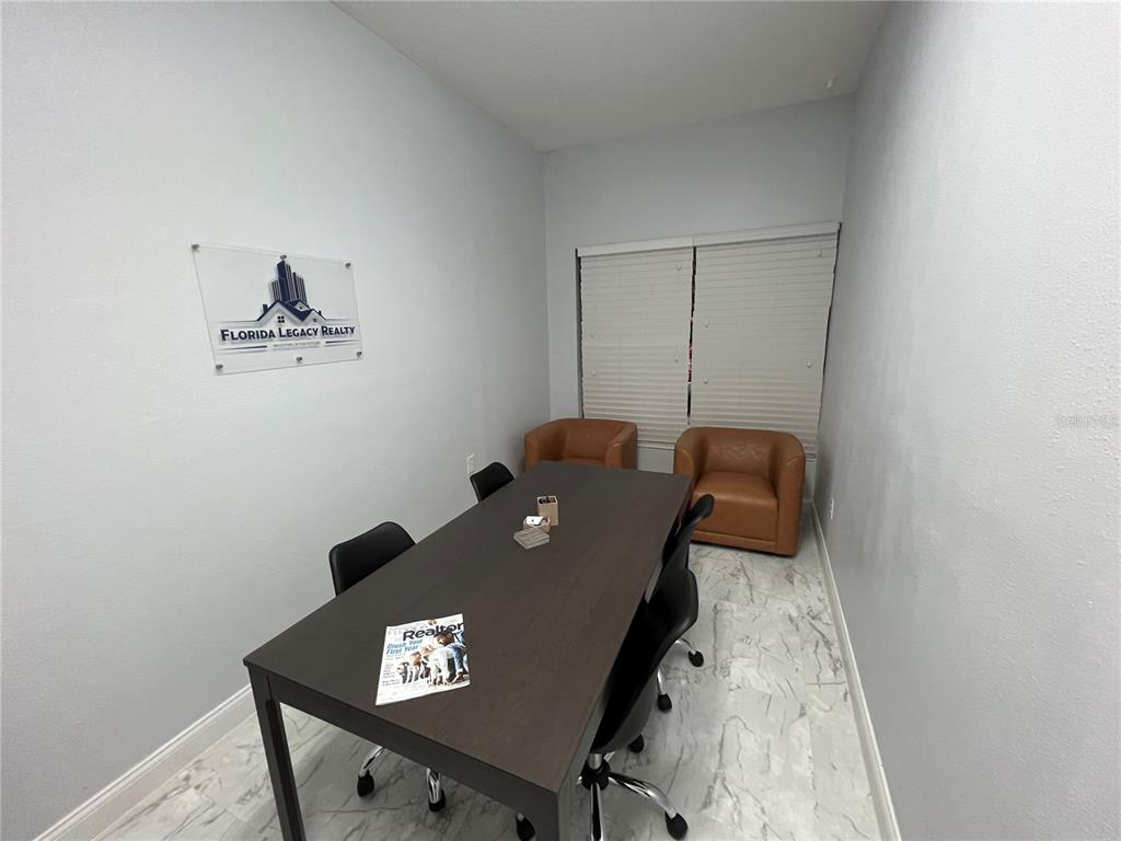 A conference room features a dark table, office chairs, two leather armchairs, and marble flooring — 1004 PLAZA DRIVE UNIT 105, KISSIMMEE, FL