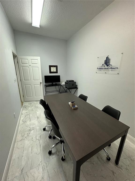 A small office features a long conference table, four chairs, and a Florida Legacy Realty sign — 1004 PLAZA DRIVE UNIT 105, KISSIMMEE, FL