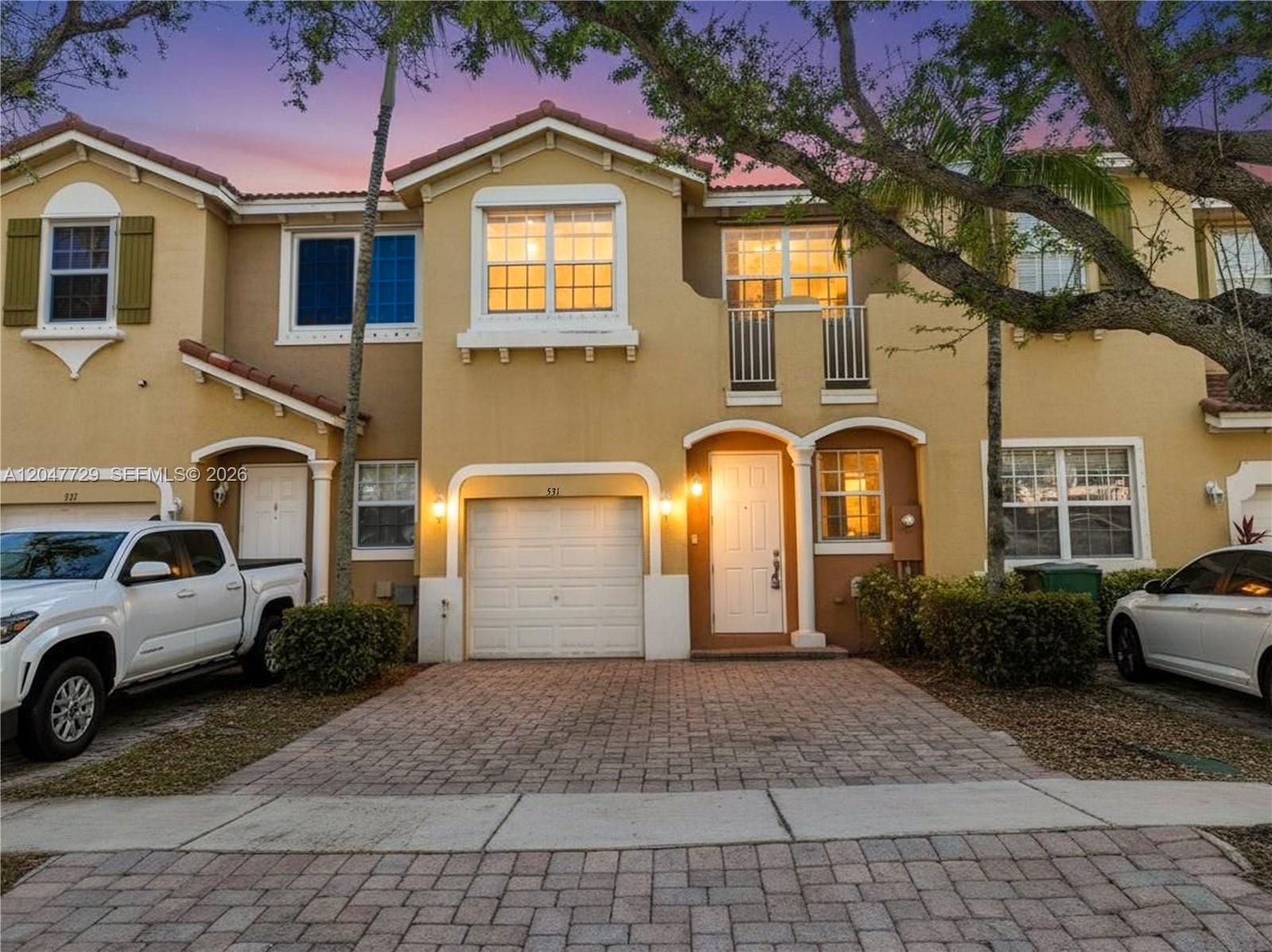 A two-story townhouse with a paved driveway, a single-car garage, and a small balcony — 531 NE 21st Ave, Homestead FL 33033, HOMESTEAD, FL