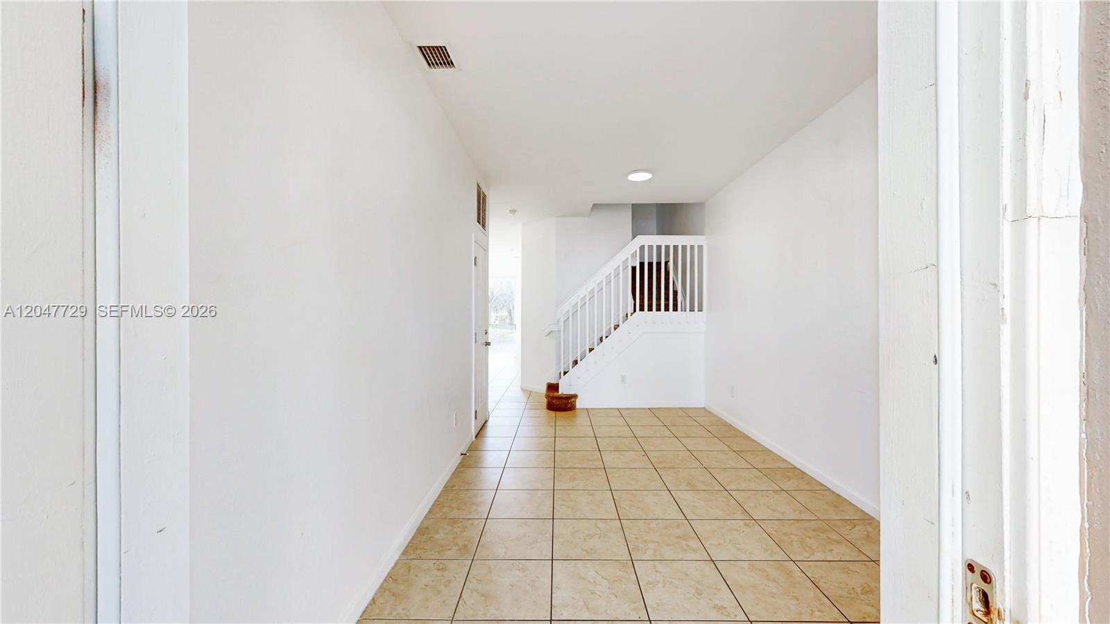 A tiled entryway leads to a white staircase with a wooden railing — 531 NE 21st Ave, Homestead FL 33033, HOMESTEAD, FL