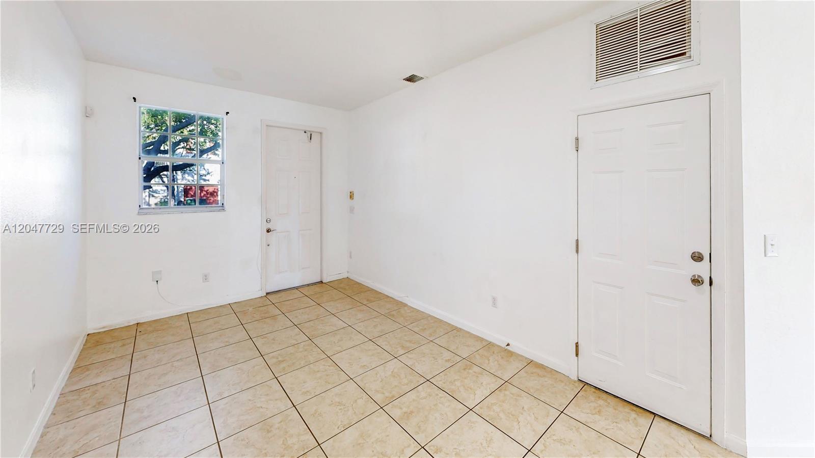 This room features white walls, tan tiled flooring, a window, and two white doors — 531 NE 21st Ave, Homestead FL 33033, HOMESTEAD, FL