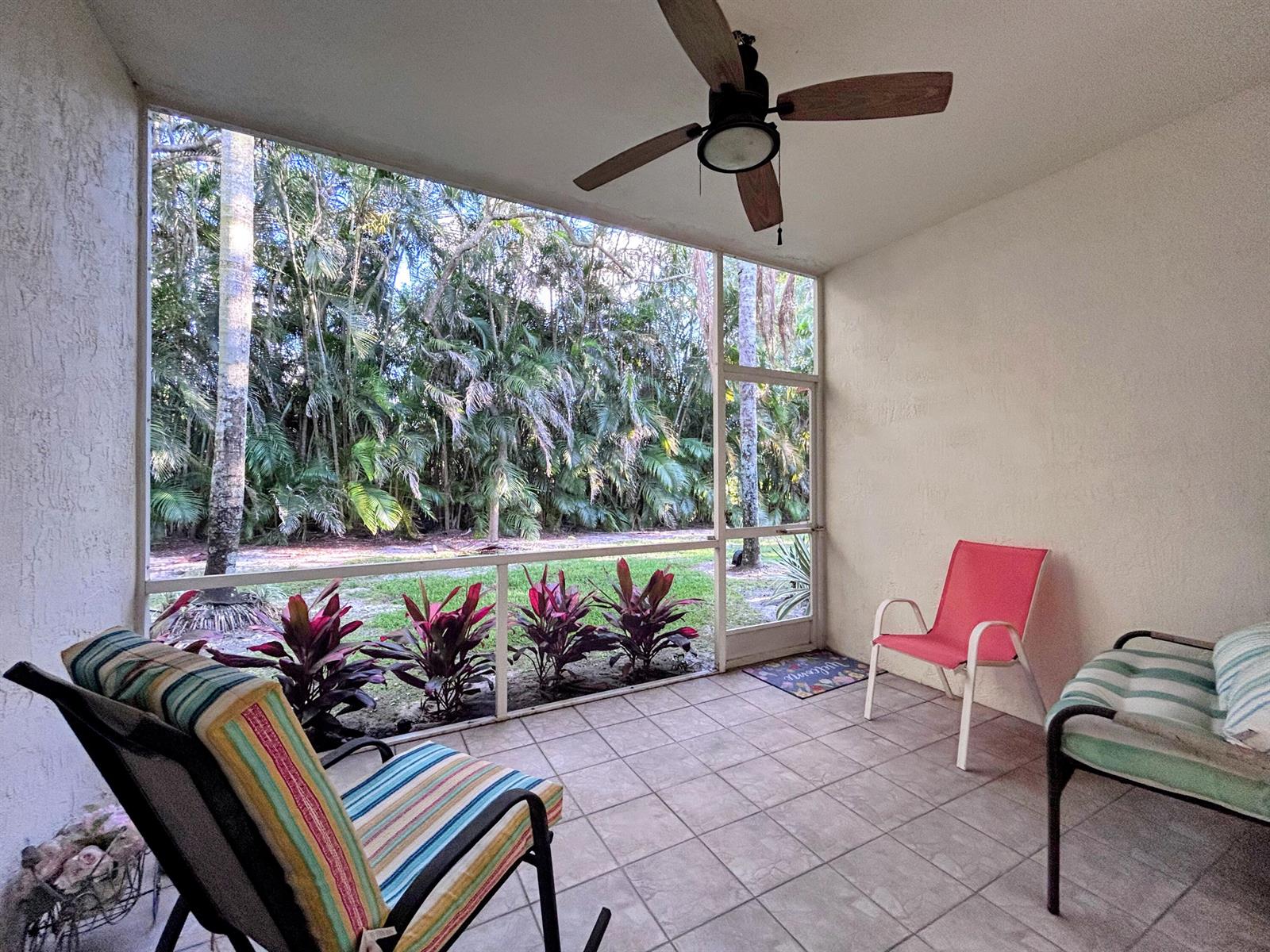 A screened-in patio with tile flooring, a ceiling fan, and views of lush tropical foliage — 7910 Laina Lane # 2, Boynton Beach FL 33437, BOYNTON BEACH, FL