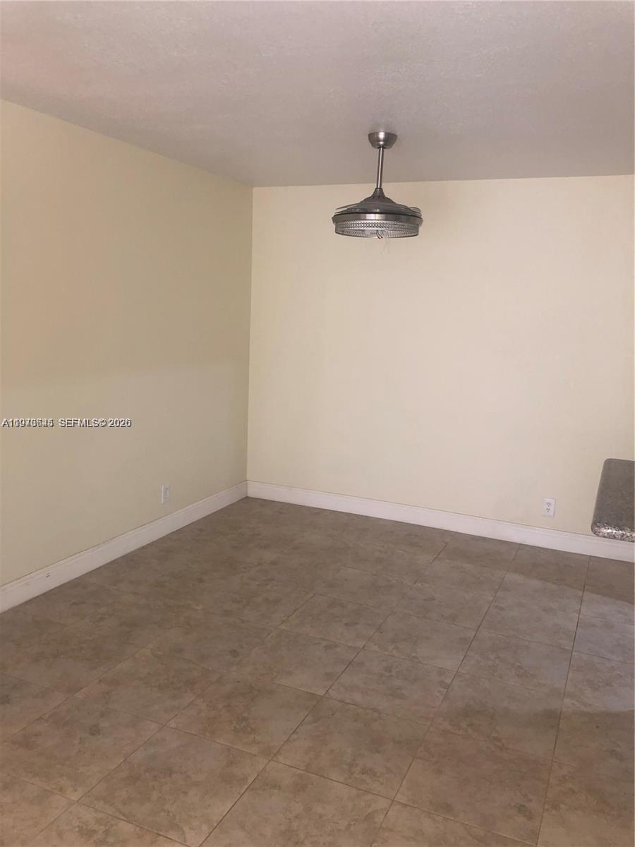 An empty room features beige walls, tile flooring, and a ceiling fan with a light — 2834 NW 55th Ave # 1C, Lauderhill FL 33313, LAUDERHILL, FL