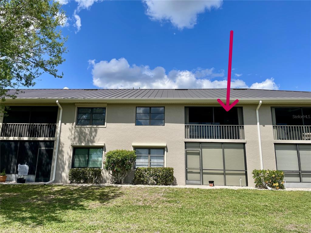 A two-story building exterior features a screened-in balcony on the upper level — 1335 SAXONY CIRCLE UNIT 322, PUNTA GORDA, FL