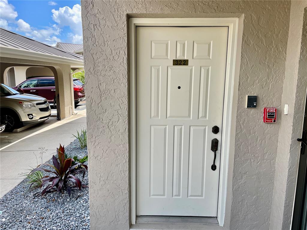 An exterior view of a white front door labeled 322 with a fire alarm nearby — 1335 SAXONY CIRCLE UNIT 322, PUNTA GORDA, FL