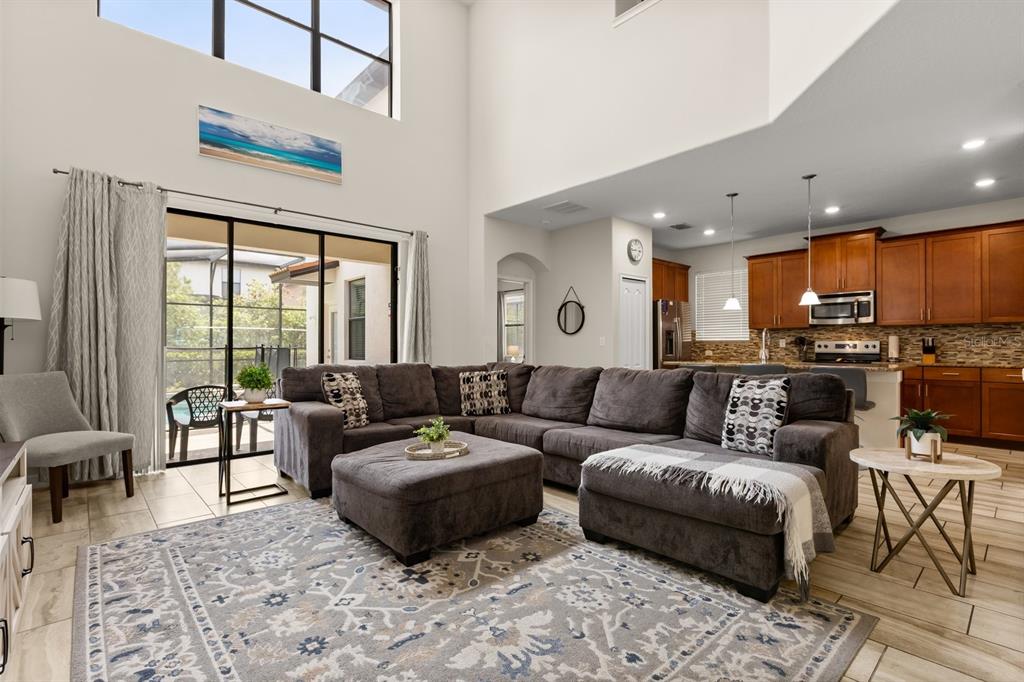 A living room with high ceilings, a large sectional sofa, and an open-concept kitchen — 5493 SOLTERRA CIRCLE, DAVENPORT, FL