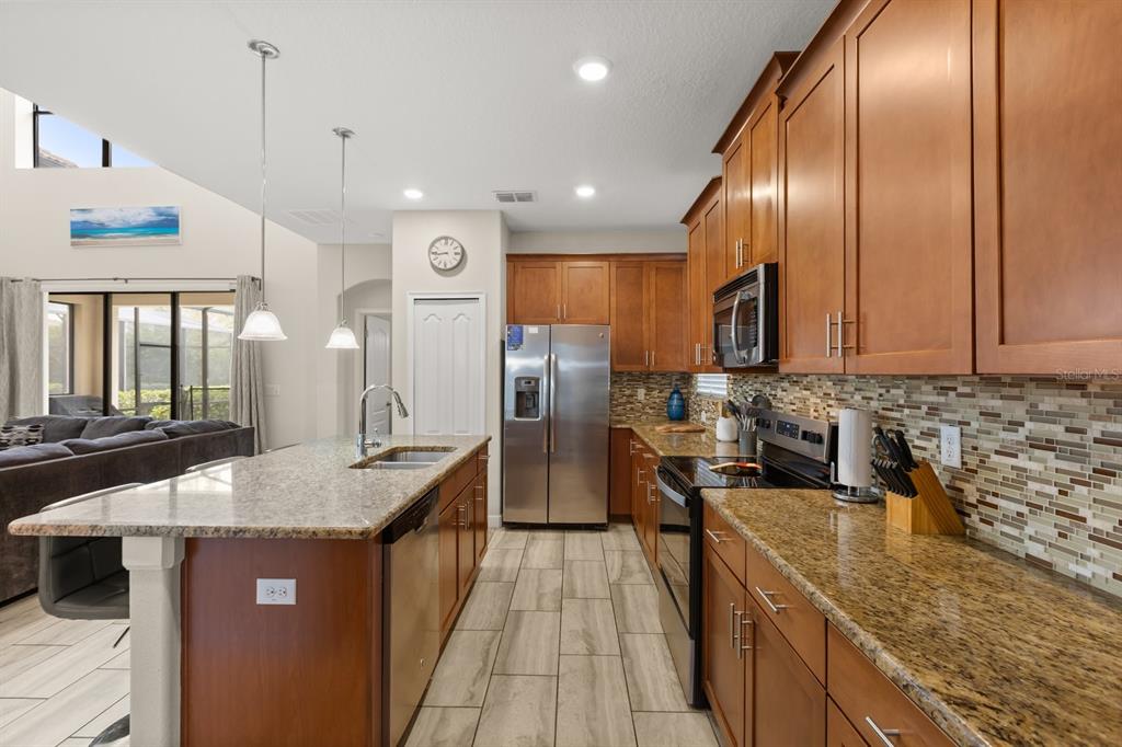A kitchen features wood cabinets, granite countertops, stainless steel appliances, and a central island — 5493 SOLTERRA CIRCLE, DAVENPORT, FL