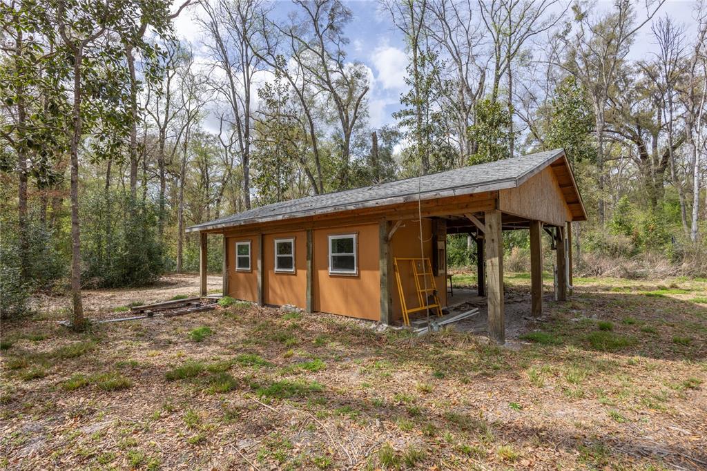 A small, orange-sided shed with three windows and an attached open-air carport — 1187 SW BOSTON TERRACE, FORT WHITE, FL