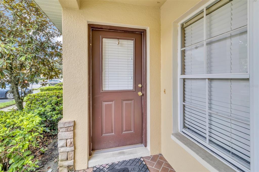 A brown front door with a glass insert sits next to a window on a porch — 5333 RIVER ROCK ROAD, LAKELAND, FL