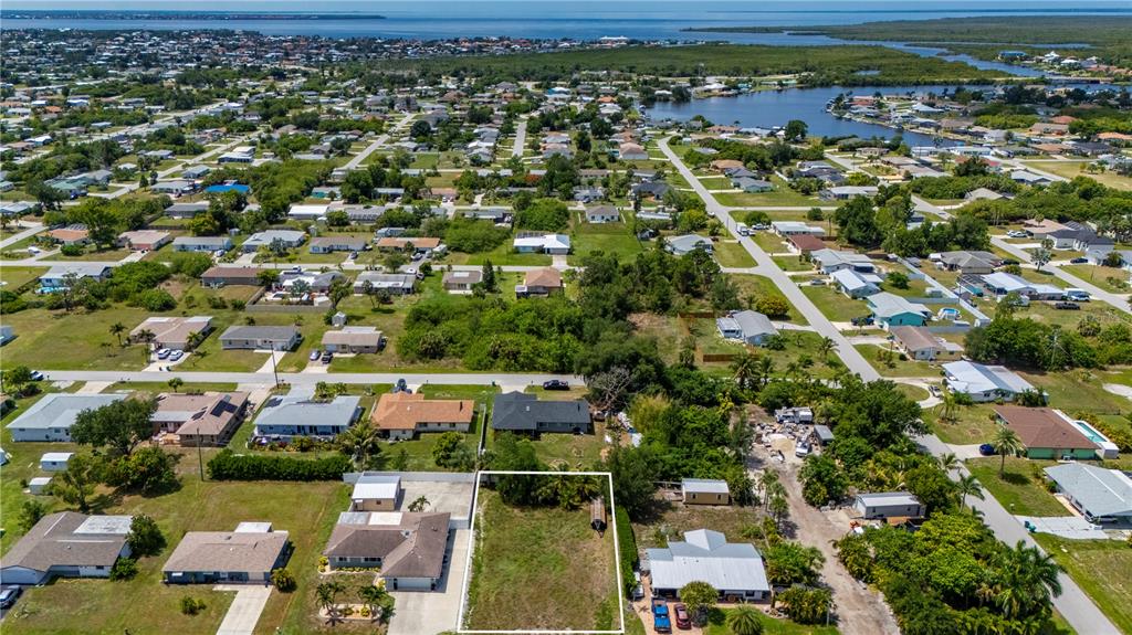 An aerial view shows a vacant rectangular lot surrounded by residential houses and vegetation — 209 CYPRESS AVENUE NW, PORT CHARLOTTE, FL