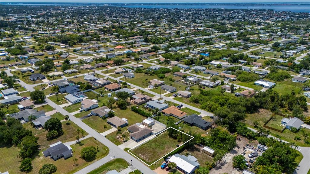 An aerial view shows a vacant, rectangular residential lot outlined in white within a neighborhood — 209 CYPRESS AVENUE NW, PORT CHARLOTTE, FL