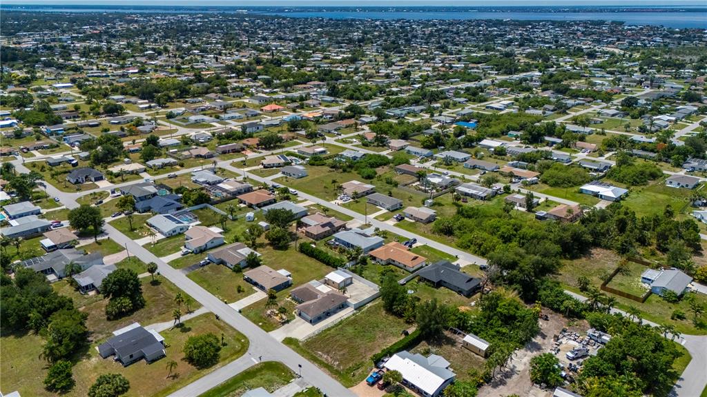 An aerial view shows a residential neighborhood with single-family homes, paved streets, and green vegetation — 209 CYPRESS AVENUE NW, PORT CHARLOTTE, FL