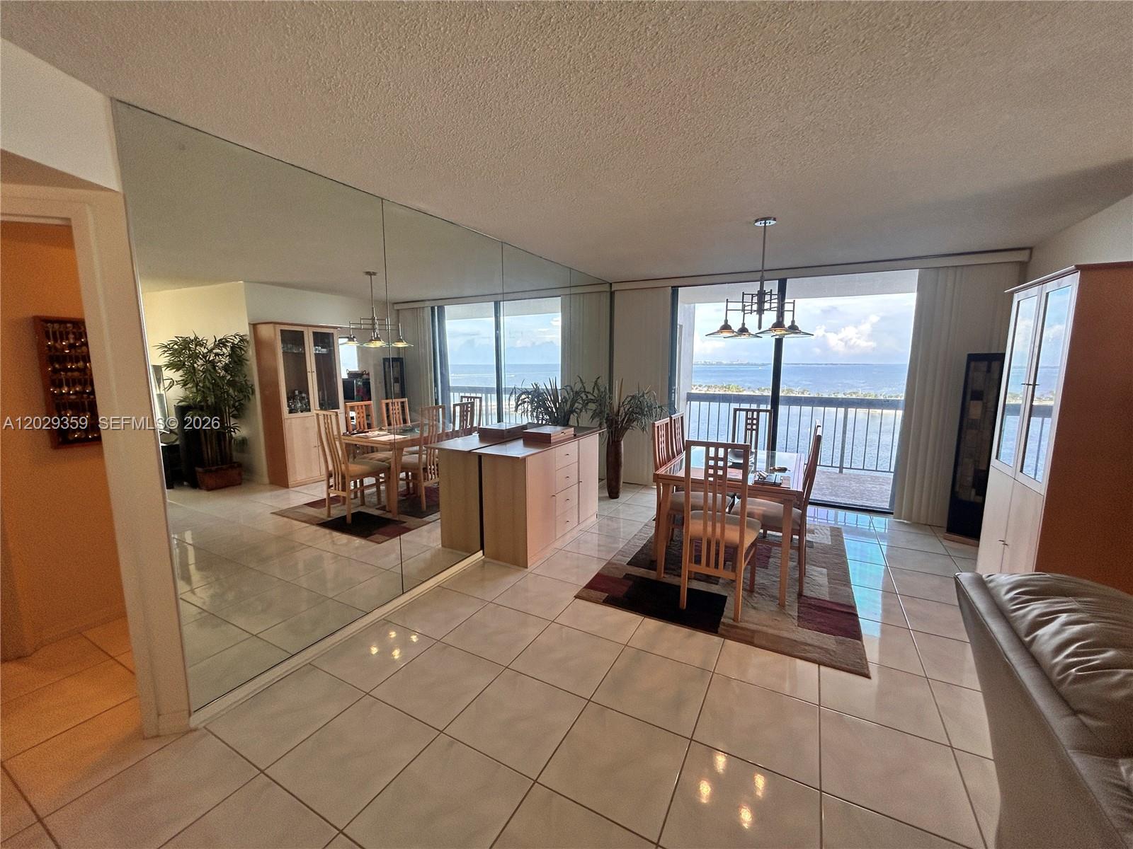 A dining area features a mirrored wall, tile flooring, and a balcony overlooking the ocean — 2333 Brickell Ave # 1402, Miami FL 33129, MIAMI, FL