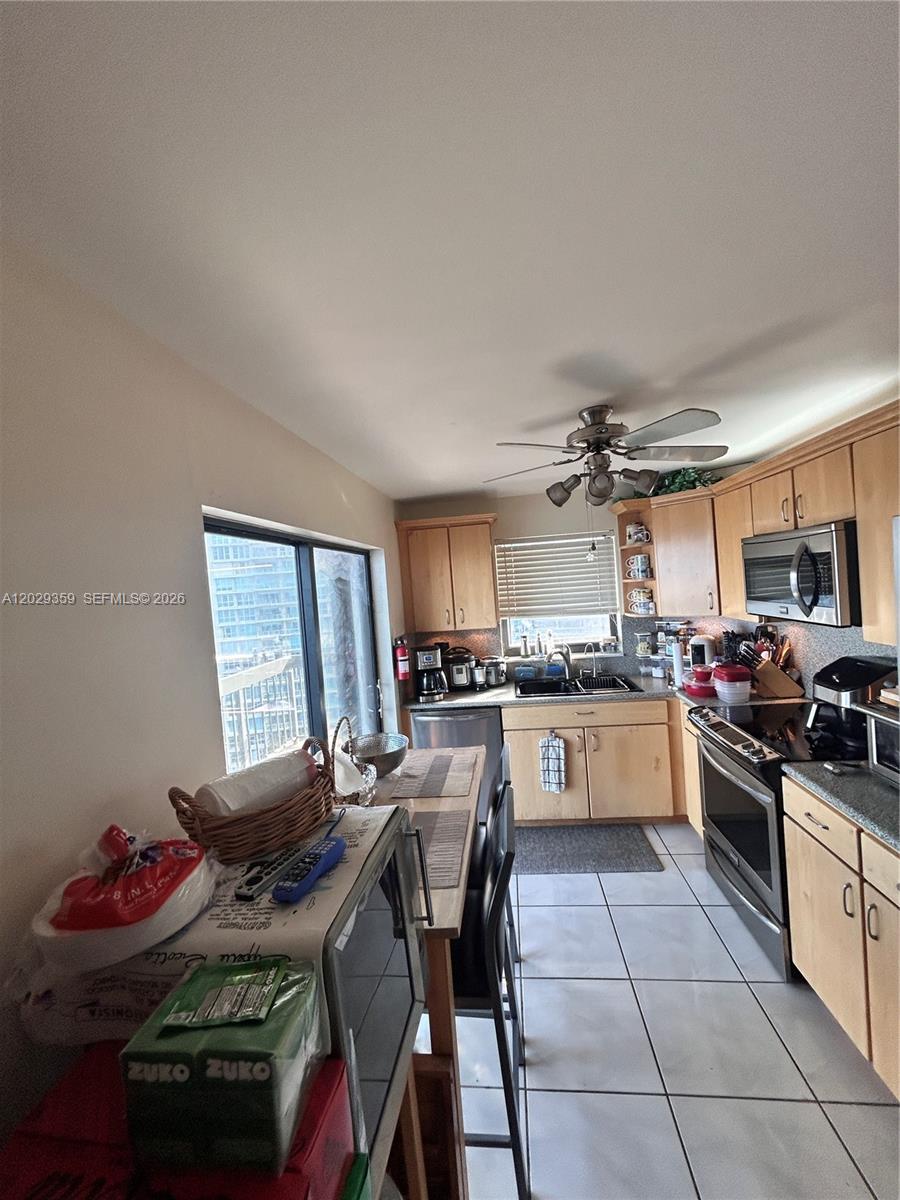 A kitchen features light wood cabinets, stainless steel appliances, tile flooring, and a dining table — 2333 Brickell Ave # 1402, Miami FL 33129, MIAMI, FL