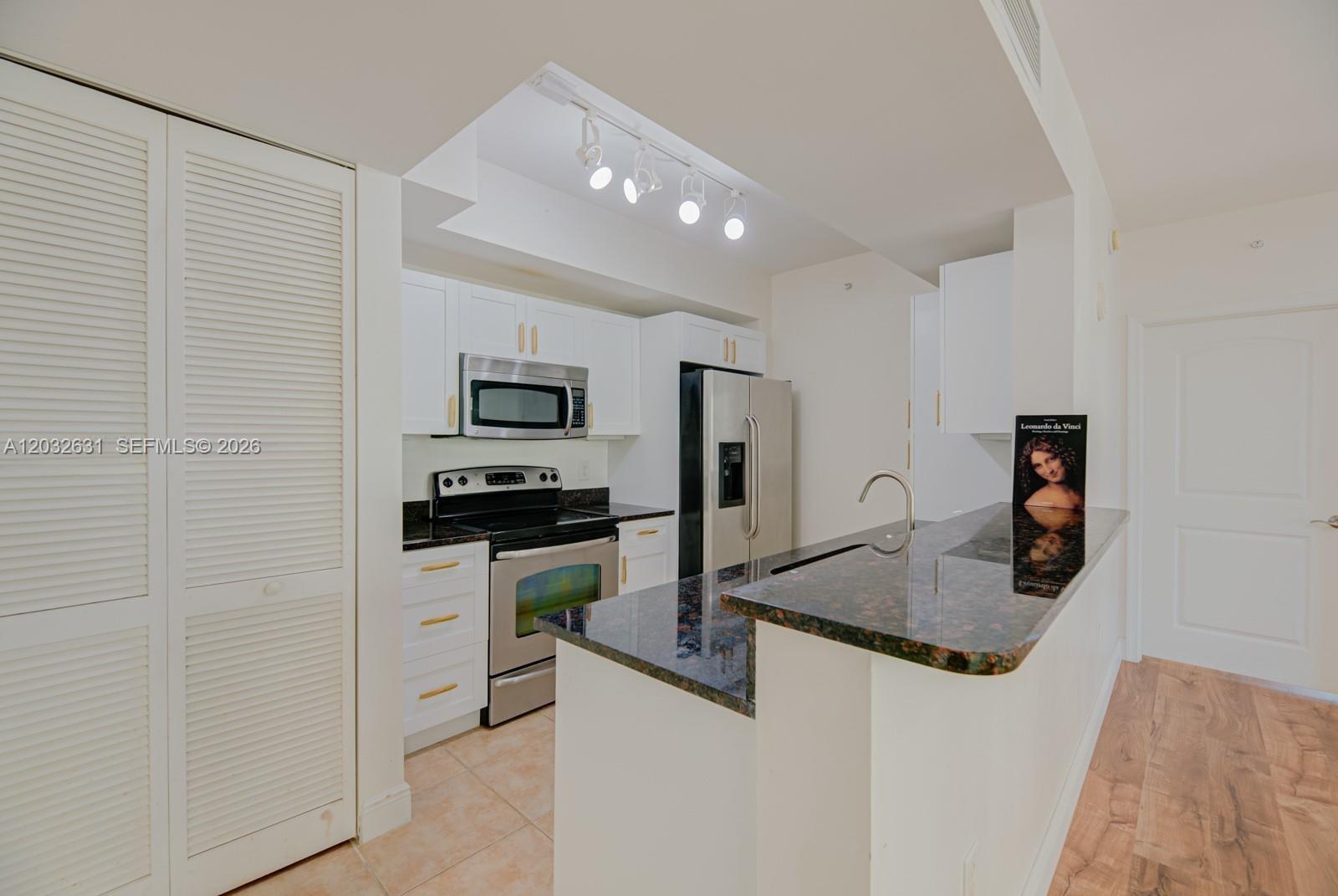 A kitchen features white cabinetry, stainless steel appliances, and a dark granite countertop — 7350 SW 89th St # 2110S, Miami FL 33156, MIAMI, FL