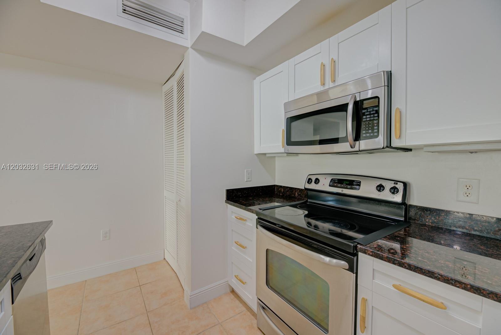 A kitchen features white cabinets, stainless steel appliances, and dark granite countertops — 7350 SW 89th St # 2110S, Miami FL 33156, MIAMI, FL