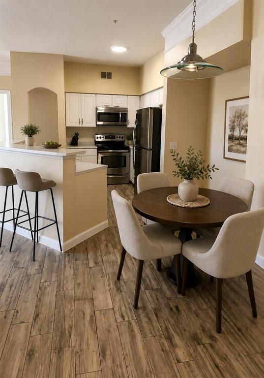 A kitchen features white cabinets, marble-look countertops, stainless steel appliances, and wood-look tile flooring — 3280 SOHO STREET UNIT 201, ORLANDO, FL