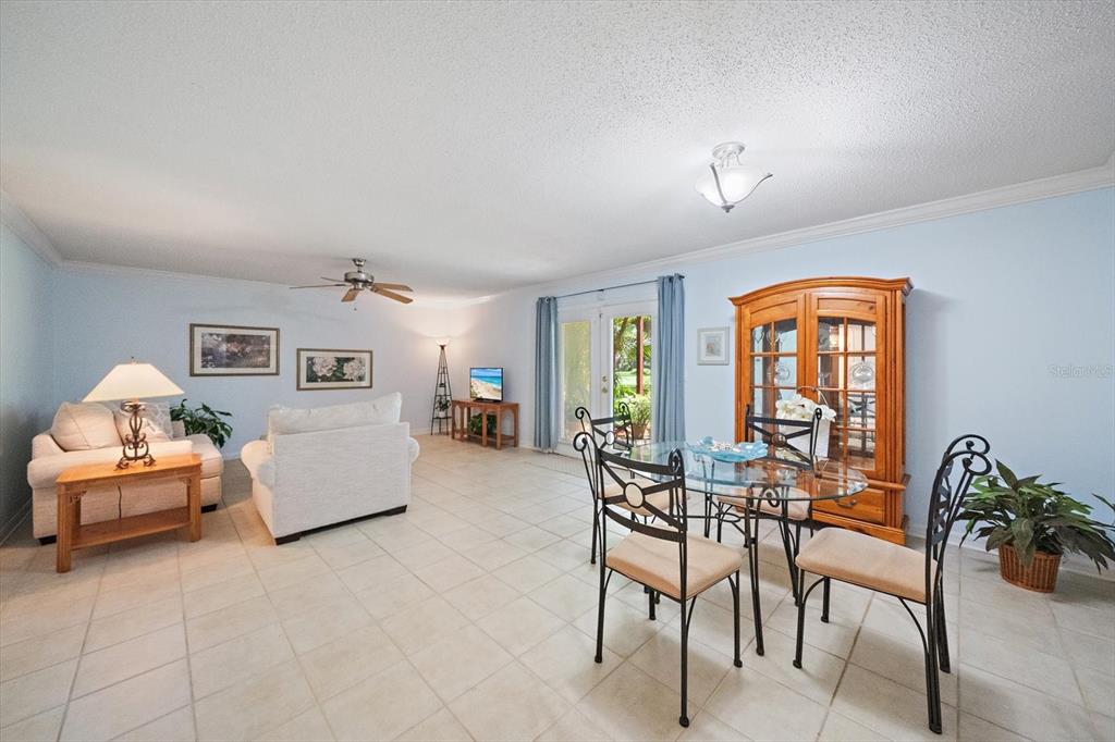 A living and dining area with light blue walls, tile flooring, and a wooden hutch — 1927 TOUCAN WAY UNIT 306, SARASOTA, FL