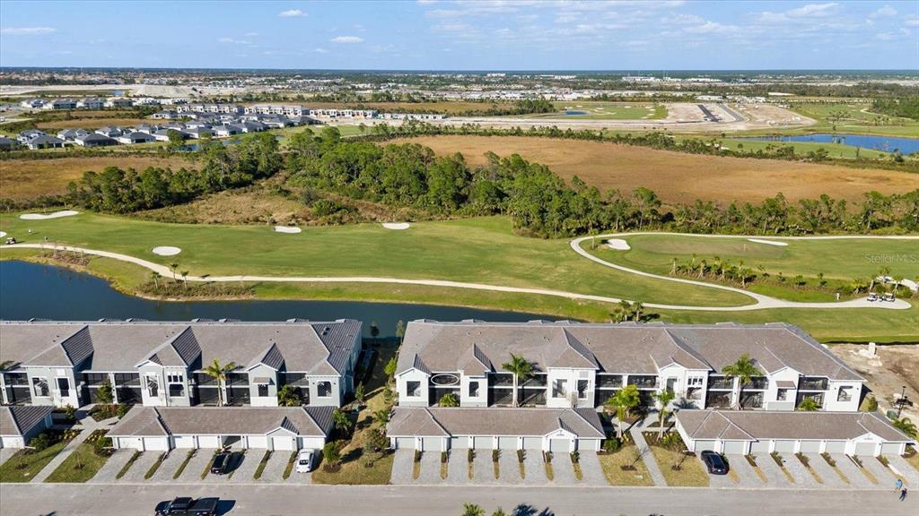 An aerial view shows a row of townhomes overlooking a golf course and pond — 12390 WELLEN GOLF STREET UNIT 201, VENICE, FL
